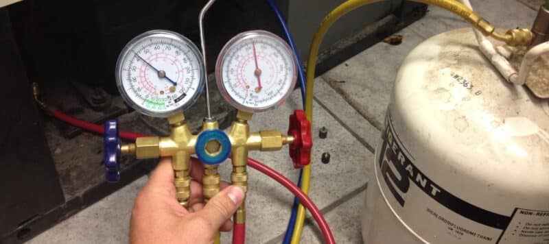 hand hodlign red and blue ac gauges to measure pressure and fluid